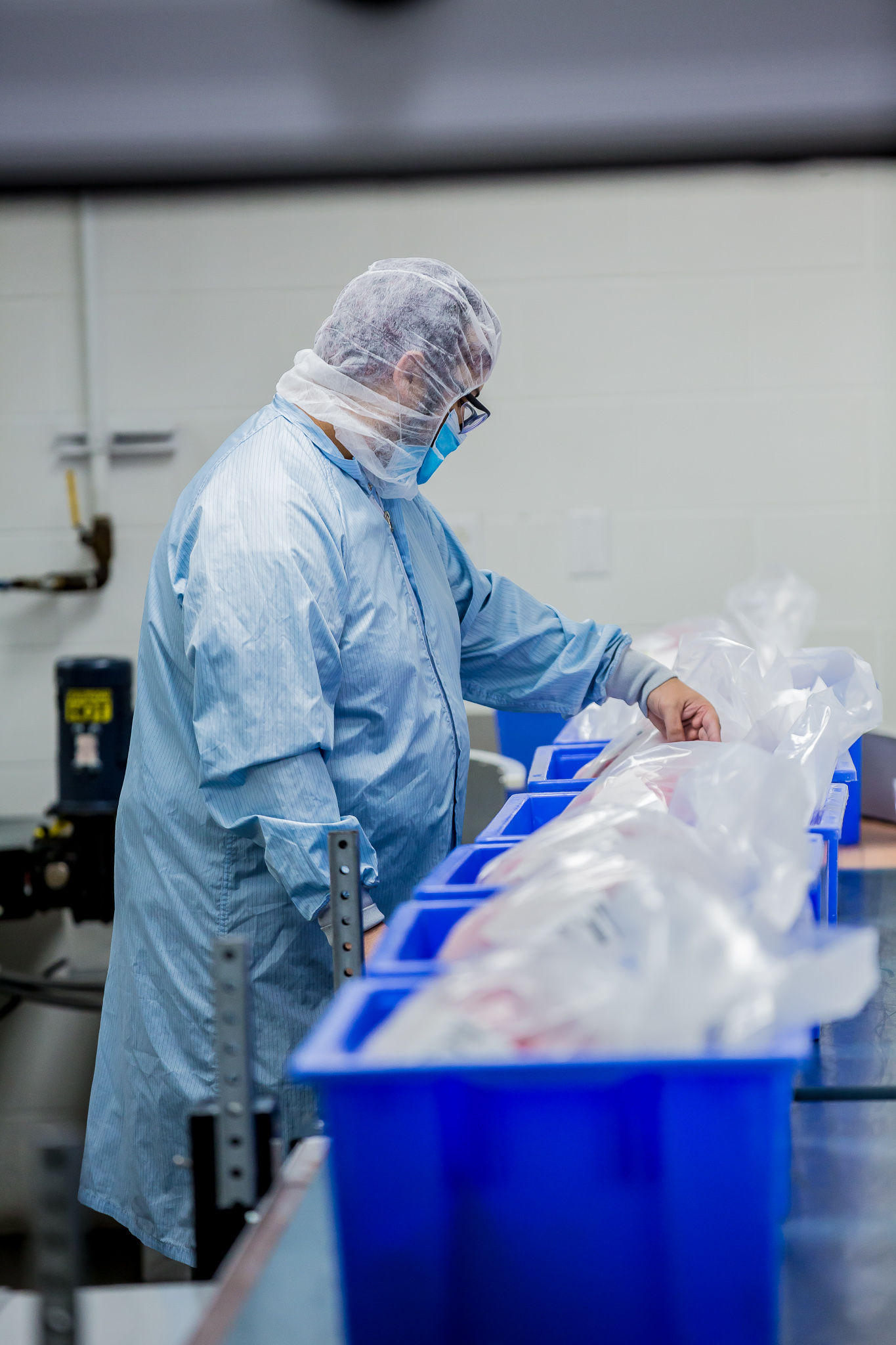 Person in clean room gear inspecting bags