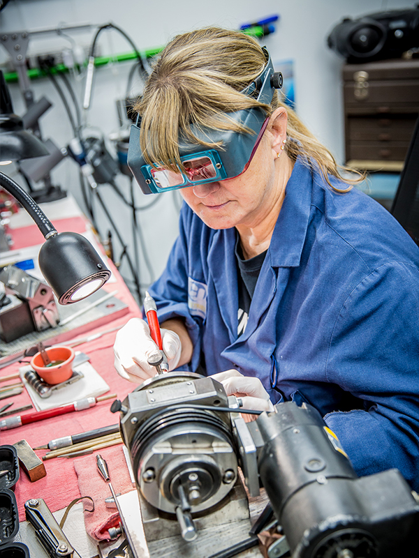 Woman wearing magnifying glasses to work on machine